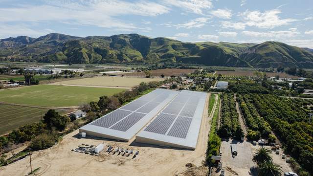Two solar-covered reservoirs with green hills behind