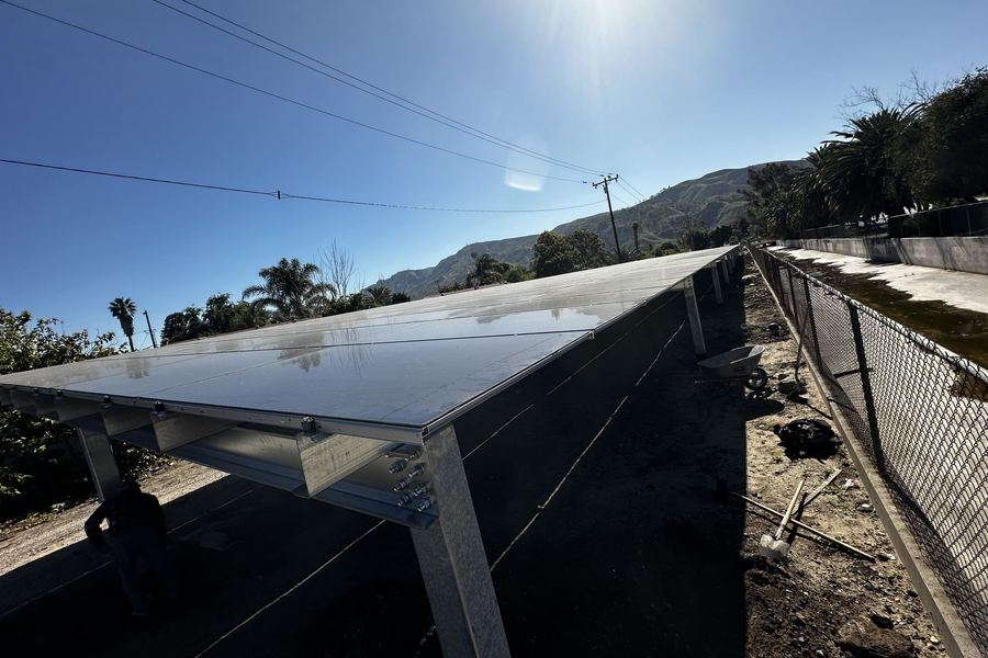 Solar modules being laid onto the canopy frame under a clear sky