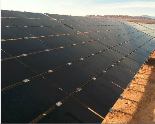 Close view of thin-film modules with desert mountains beyond